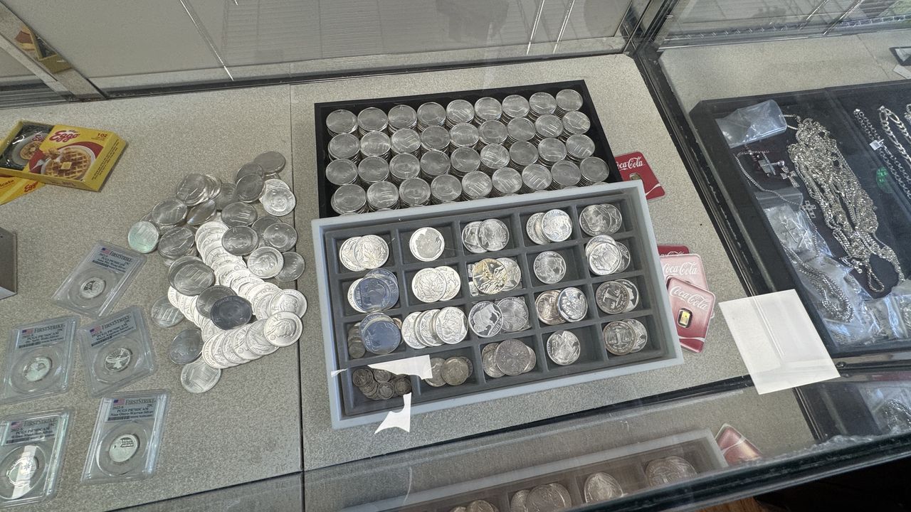 Trays of silver coins, bars, and collectibles in a display case